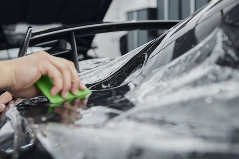 Installer working paint protection film around a vehicle panel